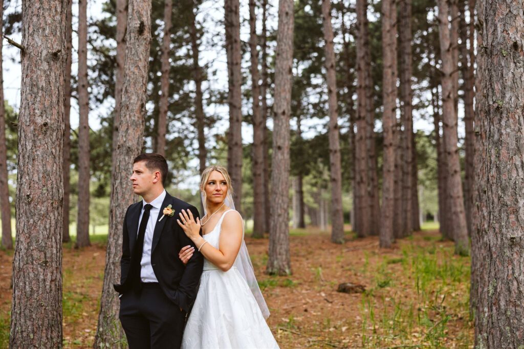 bride and groom elegantly posed in front of tall pine trees
